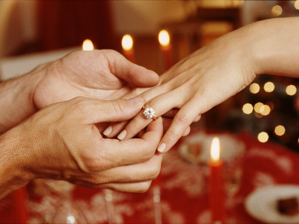 Man placing ring on woman's finger, close-up